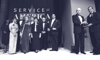 DSC Money Smart team members (l to r): Pam Bronson, Joan Lok, Kip Child, Jacqui Gordon, Cathie Davis, Teresa Perez, Jim Pilkington, and Clinton Vaughn join Chairman Powell and team leader Nelson Hernandez on stage to accept the Service to America Business and Commerce medal.