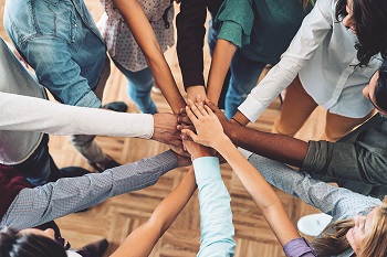 A group of people with hands together in a circle representing a team