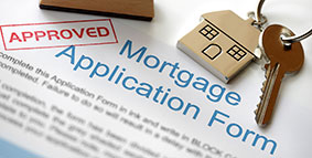 Approved mortgage loan application with house key and rubber stamp