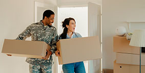 A servicemember and spouse moving boxes into a new place