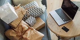 Wrapped gifts on a sofa, next to a laptop and credit card on a table